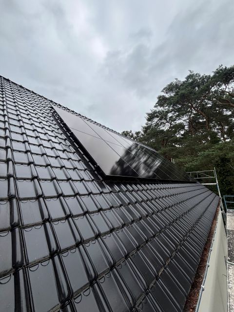Zwarte zonnepanelen op een donker pannendak